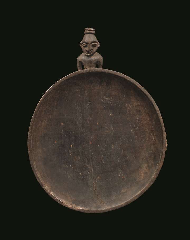A very fine and early food dish carved with a stylized ancestor figure projecting from one edge